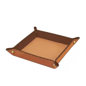 Handmade leather valet tray (or catchall tray) in cognac leather, used to organize keys, a watch, and other small essentials on a modern office desk.