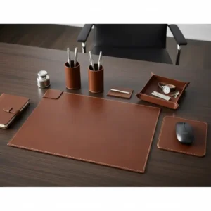 A harmonized brown leather desk set collection, featuring matching finishes on a blotter, file folder, and business card holder for a cohesive luxury look.