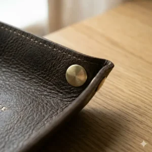 Detailed view of the durable hand-stitching and brass snaps on a custom leather valet tray.