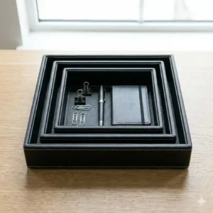 A set of three nesting black leather trays displayed in small, medium, and large sizes to show dimension variations.
